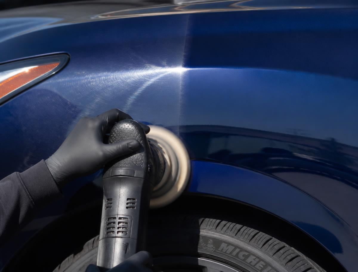 Dual action polisher correcting swirl marks on dark blue automotive paint
